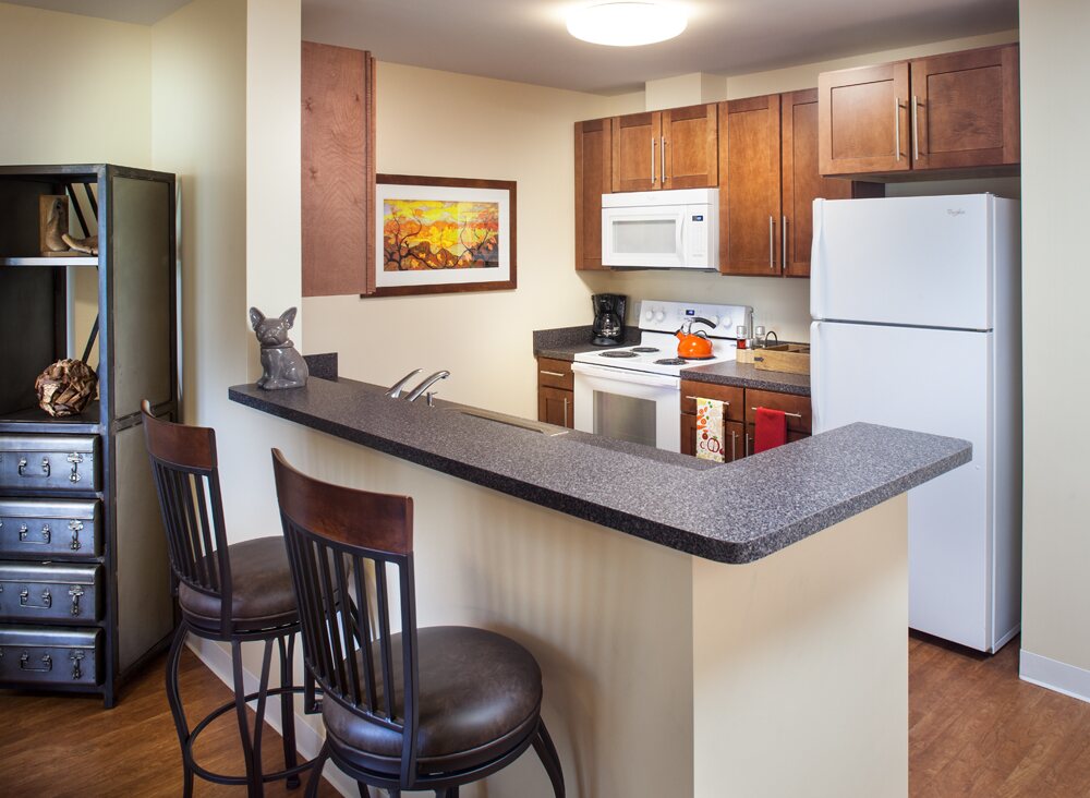 Apartment kitchen with a breakfast bar and wood cabinets