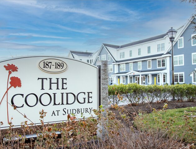 Entrance sign for The Coolidge at Sudbury at 187-189 Boston Post Road, with the apartment building behind it